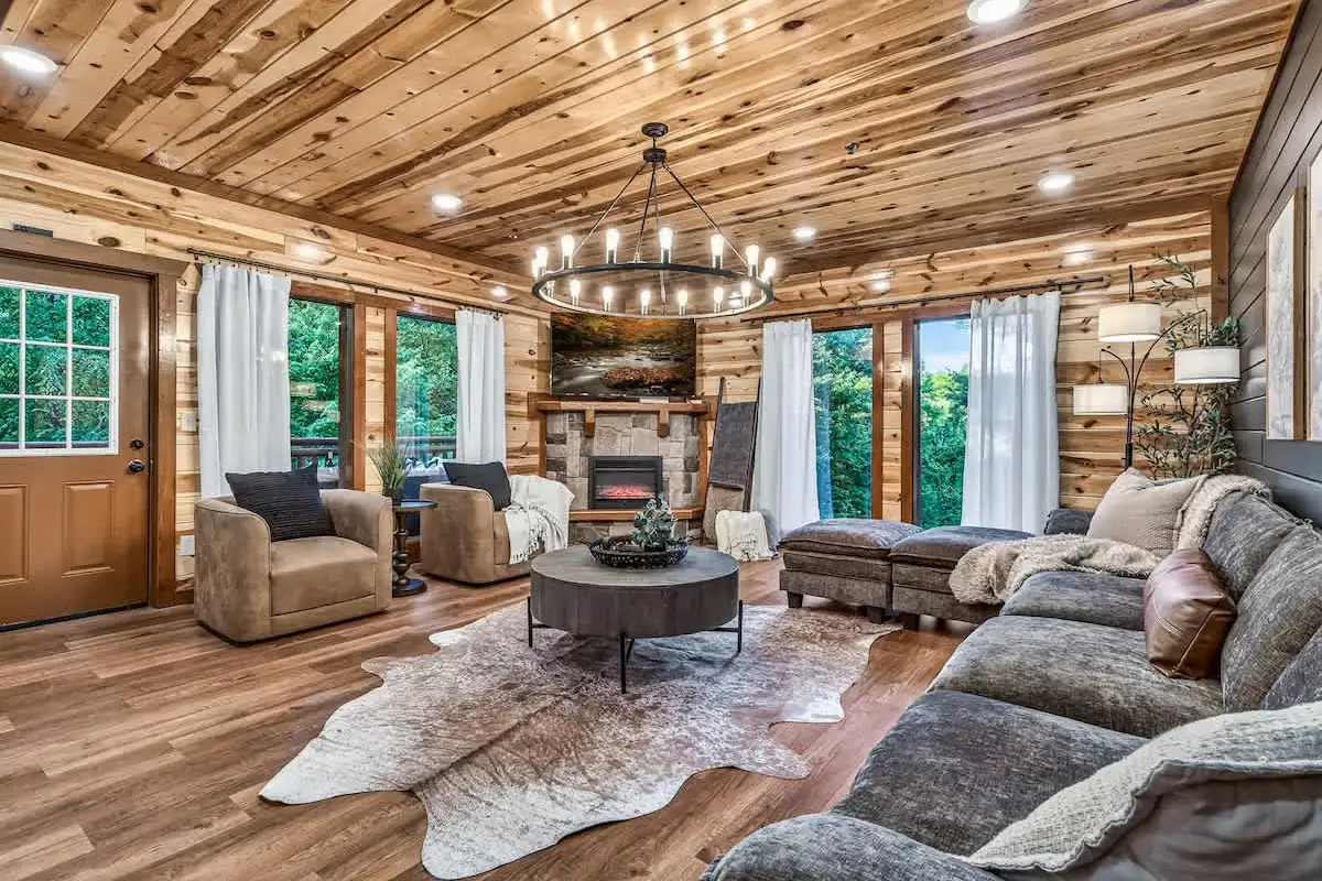 Great room at Big Star Lodge with a stone fireplace, antler chandelier and wood plank ceiling