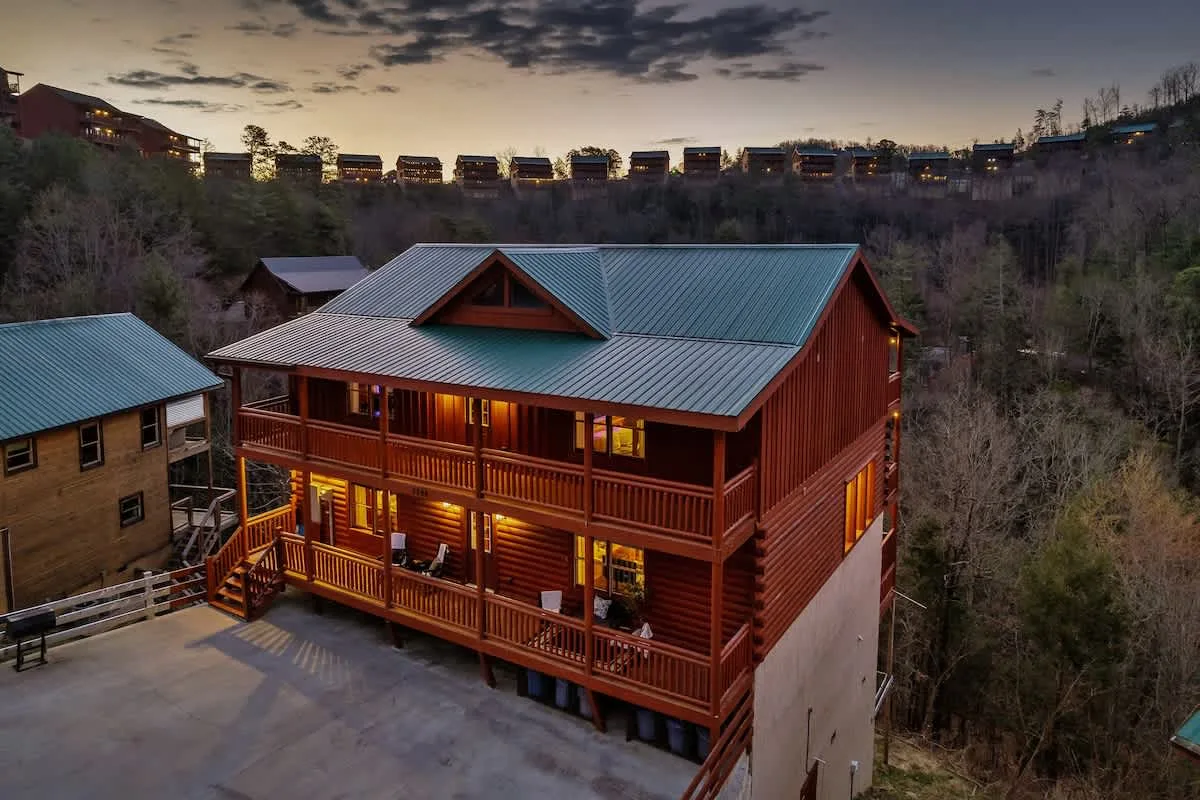 Blackhawk Lodge exterior at dusk — three levels of red log siding under a teal metal roof