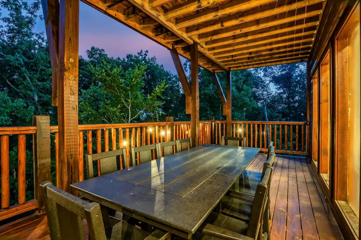 Covered deck at Blue Smoke Lodge with a long dining table lit at dusk