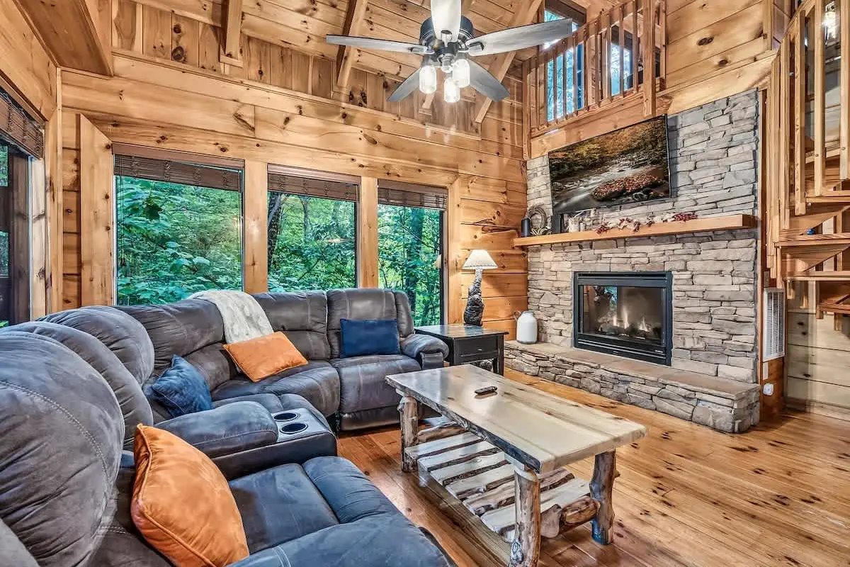 Living room at Break Point Lodge with a stacked stone gas fireplace and knotty pine walls