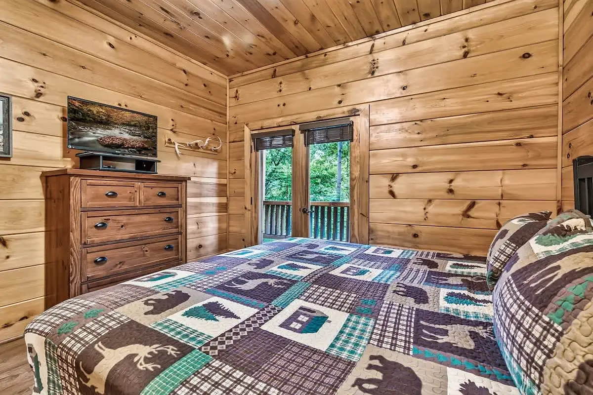 King bedroom at Break Point Lodge with quilted bedding and a mounted TV